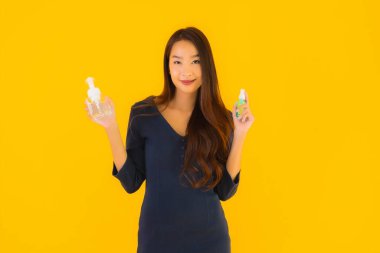 Koronavirüsten korunmak için alkol jeli ve spreyli güzel Asyalı kadın portresi veya sarı izole arka planda kovid19.