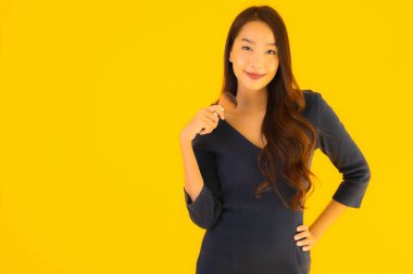 Sarı izole arkaplanda makyaj fırçası olan güzel bir Asyalı kadın portresi.