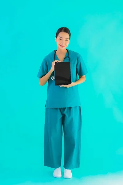 Portrait beautiful young asian doctor woman use smart tablet device on blue isolated background