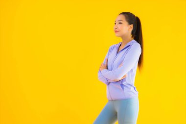 Sarı izole edilmiş arka planda spor giysili güzel Asyalı kadın portresi egzersize hazır.