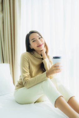 Yatak odasının iç tarafında, kahve fincanı olan Asyalı genç bir kadın.