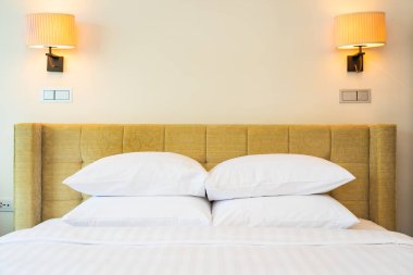 Yatak odasının içinde lamba süslemesi olan beyaz yastık ve battaniye.