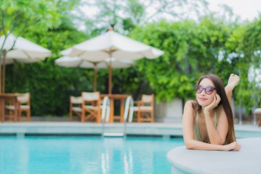 Güzel bir Asyalı kadın portresi. Rahat bir tatil için otel havuzunda yüzme havuzu etrafında gülümse.