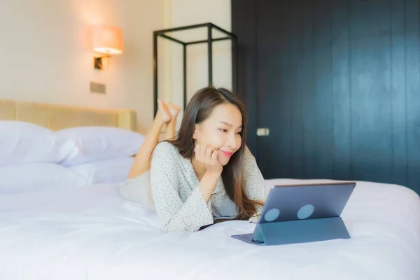 아름다운 아시아인 여성이 침실의 침대에 카드가 태블릿을 사용하는 — 스톡 사진