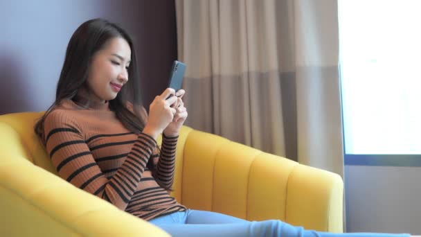 自宅でスマホを使って美しいアジア系女性の映像を — ストック動画