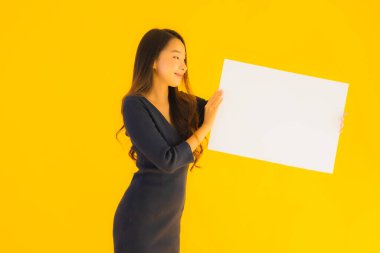 Sarı izole edilmiş arka planda boş ve boş ilan panosuyla güzel bir Asyalı kadın portresi.