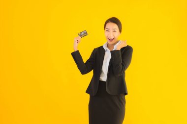 Sarı izole edilmiş arka planda kredi kartı olan güzel, genç Asyalı kadın portresi.