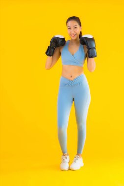 Güzel bir Asyalı kadın portresi, sarı izole edilmiş arka planda boks yaparken spor giyer.
