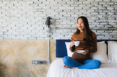 Yatak odasının iç tarafında, kahve fincanı olan Asyalı genç bir kadın.