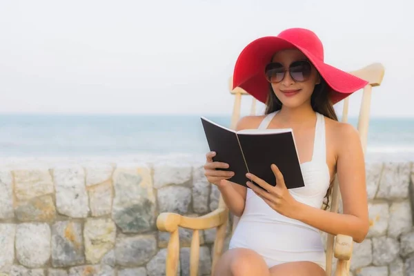 Portrait young asian woman read book around beach sea ocean in travel vacation