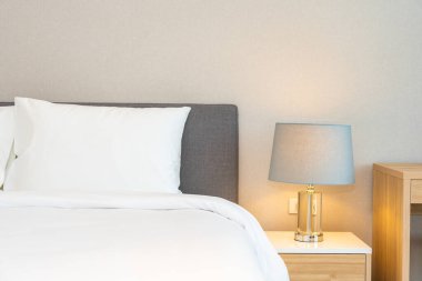 Yatak odasının iç dekorasyonuna beyaz yastık ve battaniye. İçinde lamba var.