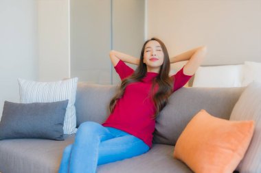 Güzel bir Asyalı kadın portresi. Yatak odasındaki kanepede rahatla. Gülümse.