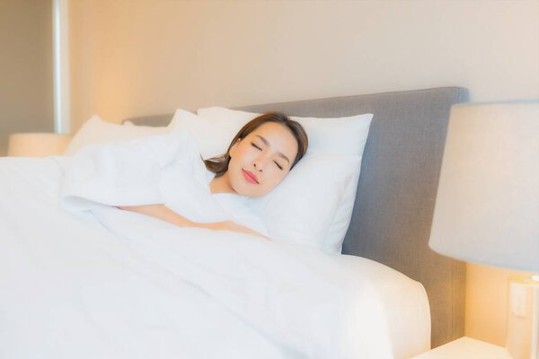 Portrait beautiful young asian woman smile relax on bed in bedroom interior