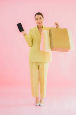 Renkli arka planda alışveriş çantası taşıyan güzel Asyalı iş kadını portresi.