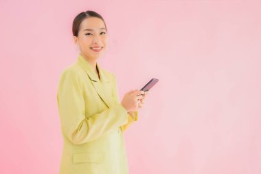 Güzel Asyalı iş kadını portresi. Arka planda kahve fincanı ve akıllı cep telefonu kullanıyor.