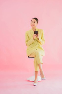 Güzel Asyalı iş kadını portresi. Arka planda kahve fincanı ve akıllı cep telefonu kullanıyor.