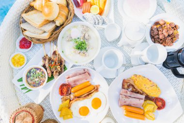 Kızarmış yumurta omletli, jambonlu, meyveli, sütlü kahveli ve yüzme havuzlu bir tepside yüzen kahvaltı.