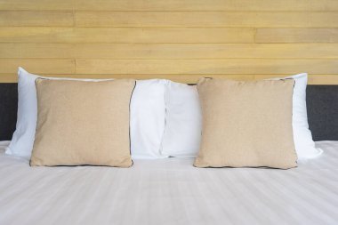 Otel odasındaki yatak odasının iç dekorasyonunda beyaz rahat yastık.