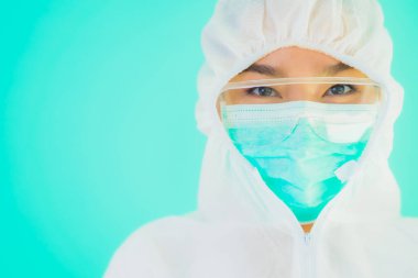 Güzel, genç Asyalı doktor kadın portre. Koronavirüsten ya da mavi arka planda kovid19 'dan korunmak için ppe ya da kişisel koruyucu ekipman takıyor.