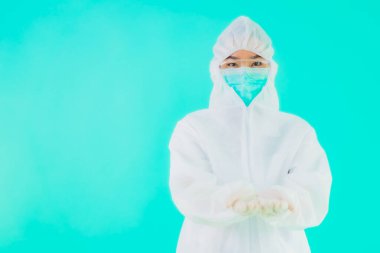Güzel, genç Asyalı doktor kadın portre. Koronavirüsten ya da mavi arka planda kovid19 'dan korunmak için ppe ya da kişisel koruyucu ekipman takıyor.