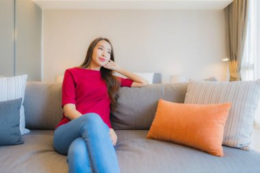 Güzel bir Asyalı kadın portresi. Yatak odasındaki kanepede rahatla. Gülümse.