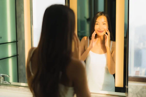 ポートレート美しいです若いですアジアの女性チェックアップ彼女の顔と顔でバスルーム内装 — ストック写真