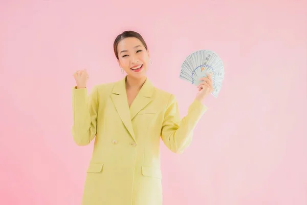 拥有大量现金或彩色照片背景的美丽的年轻亚洲女商人 — 图库照片