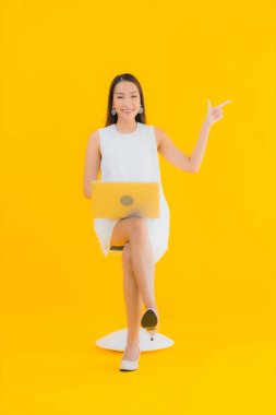 Sarı izole edilmiş arka planda bilgisayarlı güzel Asyalı kadın portresi.