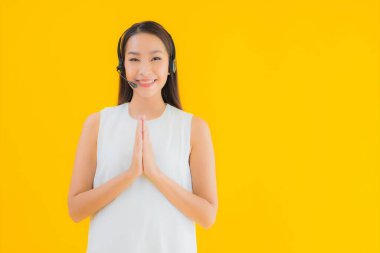 Güzel genç Asyalı kadın portresi, sarı izole arka planda yardım için çağrı merkezi.