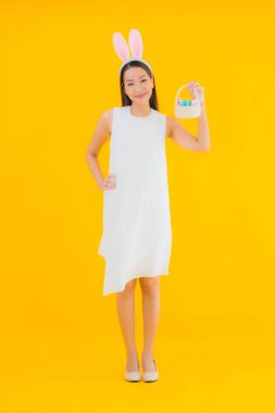 Sarı izole edilmiş arka planda paskalya yumurtası olan güzel Asyalı kadın portresi.