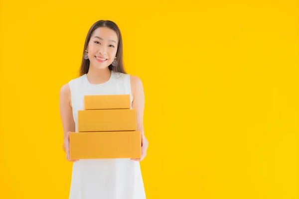肖像画美しいです若いですアジアの女性とともに小包ボックス上の黄色隔離された背景 — ストック写真