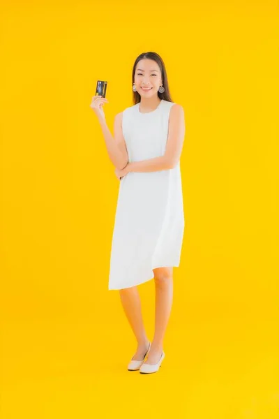 肖像画美しい若いアジアの女性とクレジットカードのためのオンラインショッピング上の黄色隔離された背景 — ストック写真