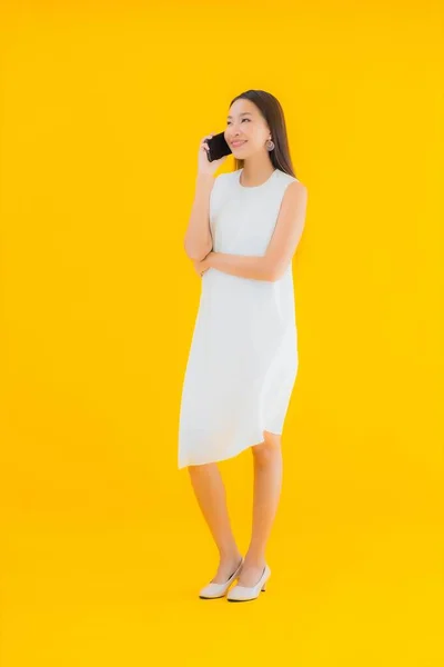 亚洲年轻貌美的女性形象 带着黄色独立背景的智能手机 — 图库照片