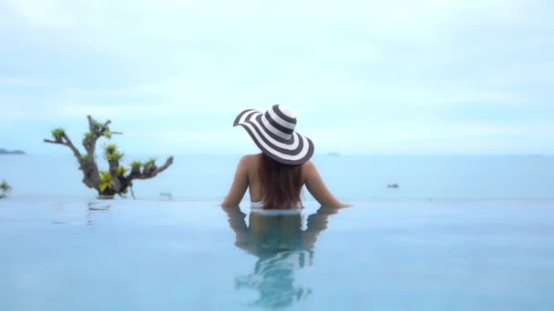 美しい若いアジアの女性の映像は休暇中のレジャーのためにホテルのリゾートでスイミングプールの周りにリラックス — ストック動画