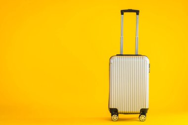 Gri renkli valiz ya da bagaj çantası kullanımı sarı izole arka planda seyahat ve boş zaman için