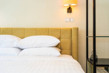 Yatak odasının içinde lamba süslemesi olan beyaz yastık ve battaniye.