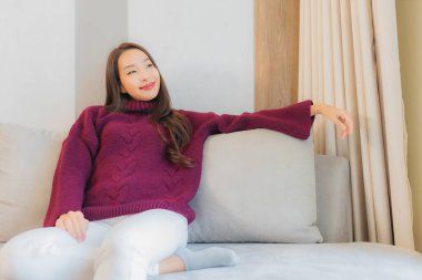 Portre güzel Asyalı kadın gülümsemesi. Oturma odasındaki kanepede rahatla.