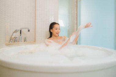Güzel bir Asyalı kadının portresi. Rahatlayın. Banyo içlerindeki küvette gülümseyin.