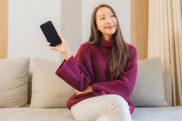 美丽动人的年轻亚洲女人在客厅的沙发上使用智能手机 — 图库照片