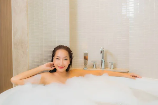 在浴室内部的浴缸里 年轻美丽的亚洲女人在浴缸里放松地笑着 — 图库照片