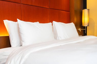 Beyaz yastık ve battaniye yatak odasının içinde lamba süslemesi olan yatakta.