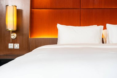 Beyaz yastık ve battaniye yatak odasının içinde lamba süslemesi olan yatakta.