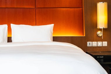 Beyaz yastık ve battaniye yatak odasının içinde lamba süslemesi olan yatakta.