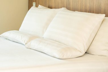 Yatak odasının içinde battaniye süslemeli beyaz rahat yastık.