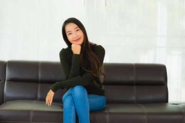 Güzel bir portre. Genç Asyalı kadın. Oturma odasındaki kanepede rahatla.