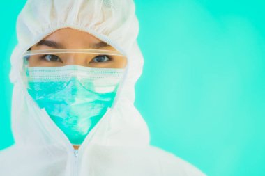 Güzel, genç Asyalı doktor kadın portre. Koronavirüsten ya da mavi arka planda kovid19 'dan korunmak için ppe ya da kişisel koruyucu ekipman takıyor.