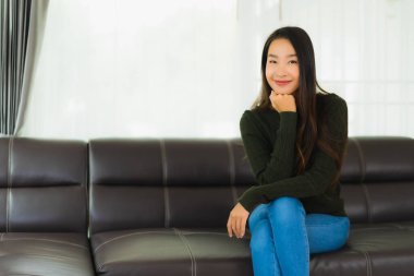 Güzel bir portre. Genç Asyalı kadın. Oturma odasındaki kanepede rahatla.