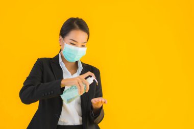 Güzel bir iş kadını portresi. Maske takıyor. Korunmak için alkol jeli kullanıyor.