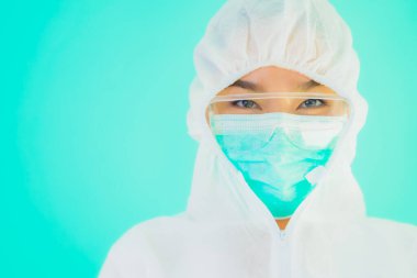 Güzel, genç Asyalı doktor kadın portre. Koronavirüsten ya da mavi arka planda kovid19 'dan korunmak için ppe ya da kişisel koruyucu ekipman takıyor.