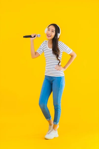 Portret Pięknej Młodej Azjatyckiej Kobiety Śpiewającej Mikrofonem Słuchawką Żółtym Odizolowanym — Zdjęcie stockowe